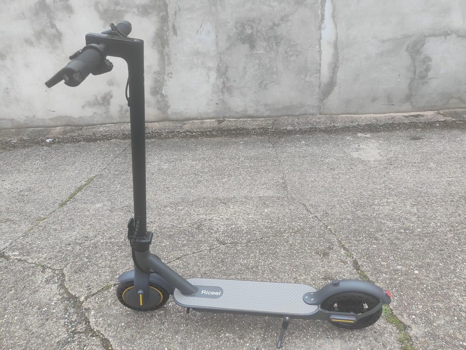 A modern electric scooter parked on a sunny city sidewalk during golden hour.
