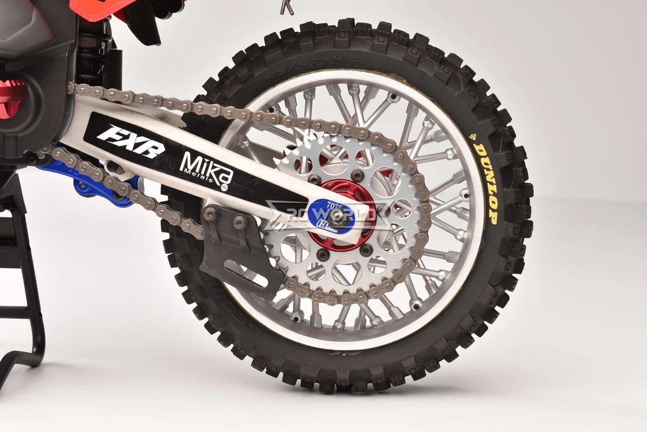 Checking dirt bike spoke tension by tapping a metal wrench against a wheel spoke.