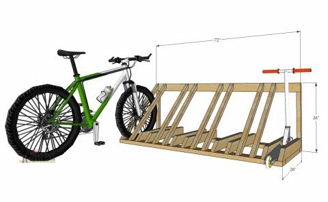 A completed wooden bike rack holding a bicycle upright in a bright workshop.
