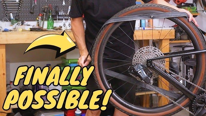 A hand using a wrench to loosen the axle nut on a bicycle wheel.