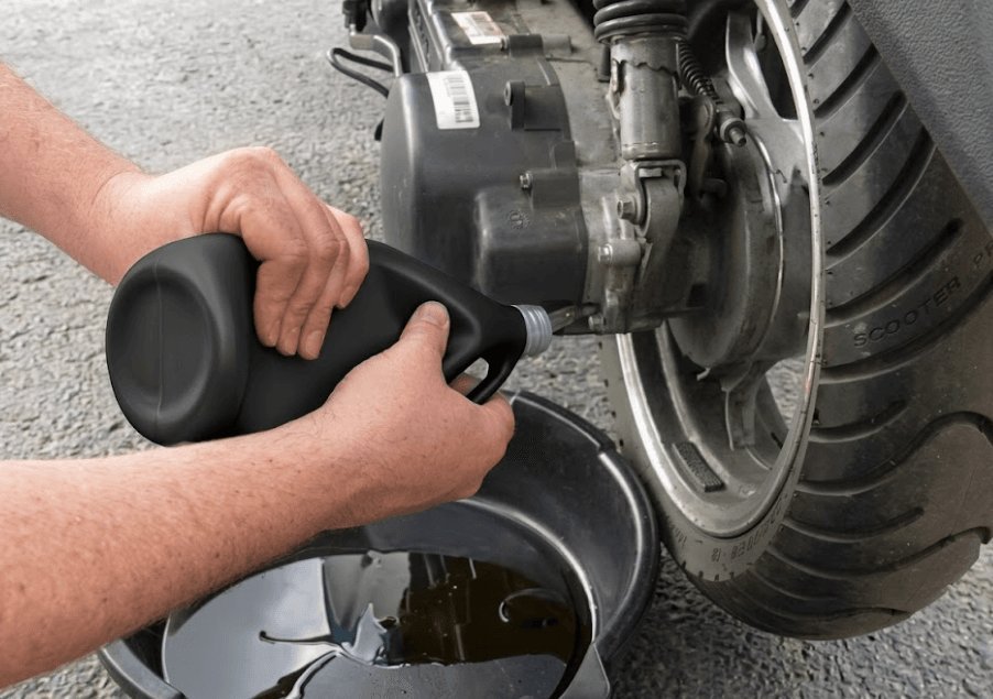 Checking the clean oil level on a scooter dipstick after an oil change.