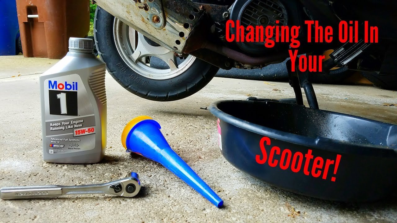 A mechanic performing a routine oil change on a modern scooter in a garage.