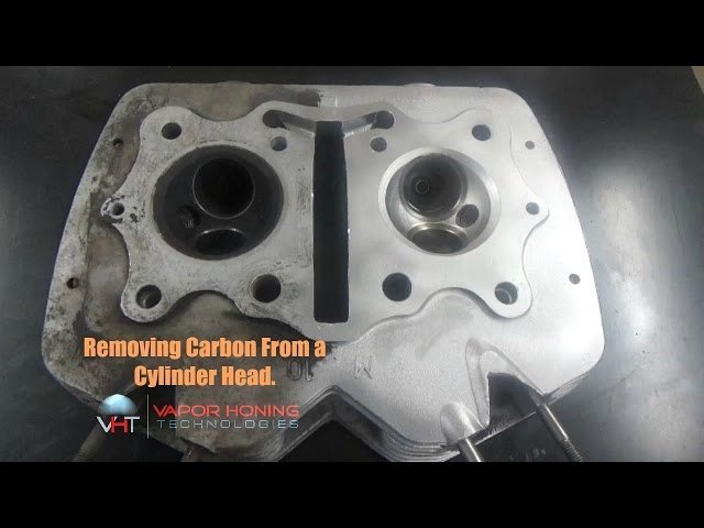A mechanic inspects a clean dirt bike cylinder head during a maintenance session.