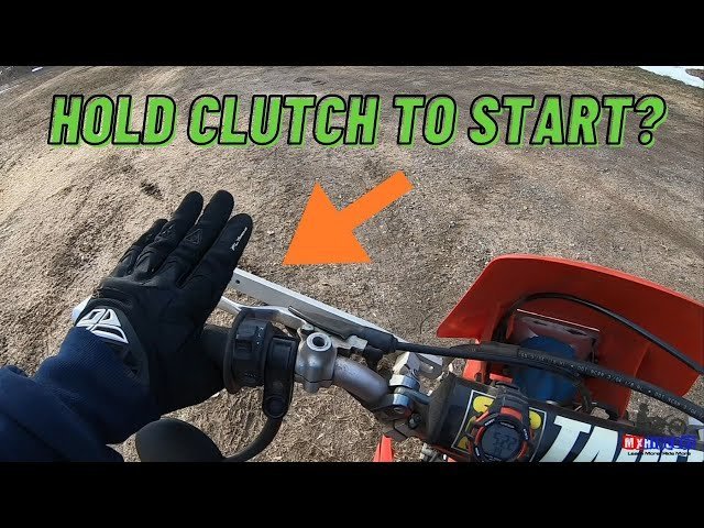 A rider successfully starting a dirt bike on a gentle downward slope.