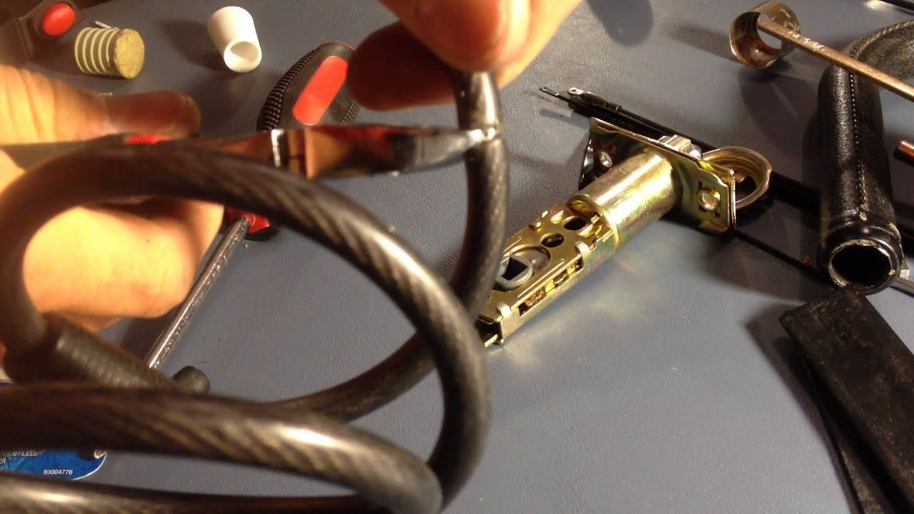 An angle grinder cutting through a thick steel bike cable lock with sparks.