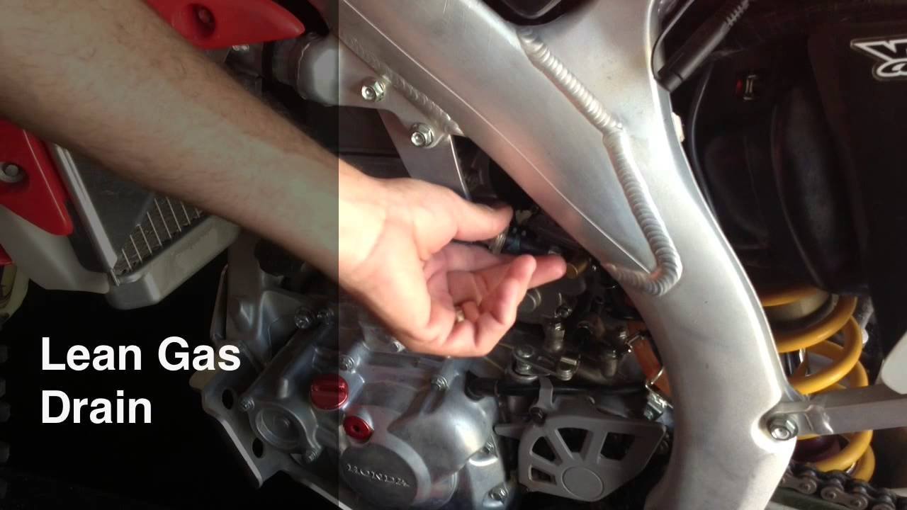 Mechanic reviewing maintenance procedures for dirt bike fuel systems in a garage.