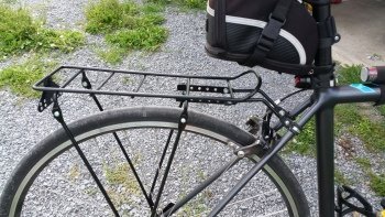 Checking the stability of a securely mounted rear bike rack on a bicycle.