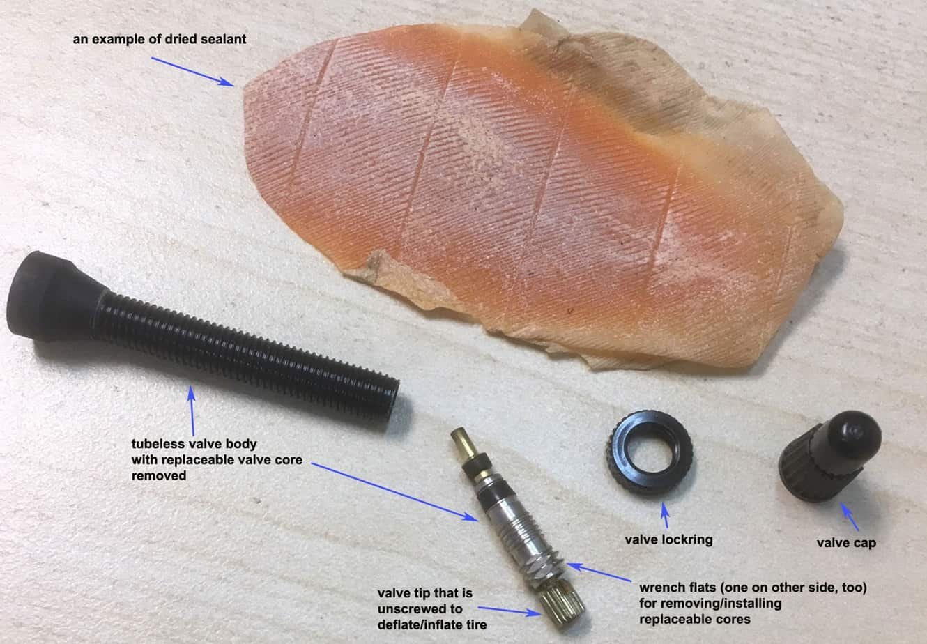 Hands carefully replacing a bicycle valve stem on a wheel rim.