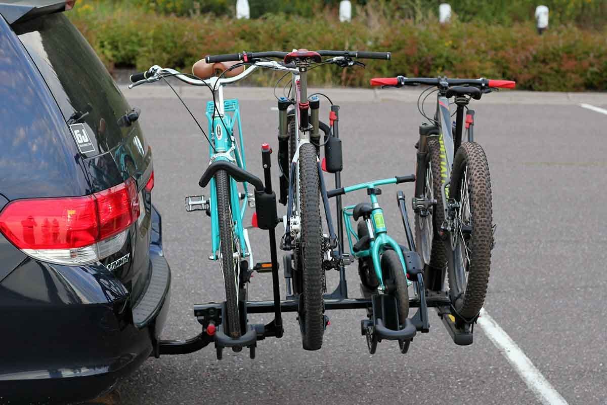 A secure hitch-mounted bike rack installed on the back of a modern minivan.