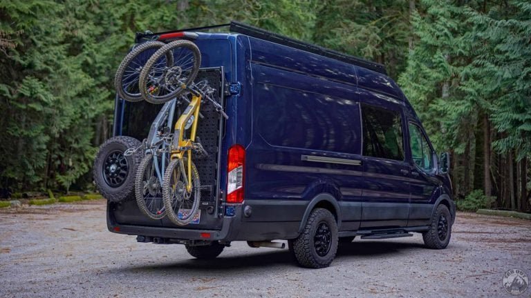 Hands testing the stability of a securely installed van bike rack.