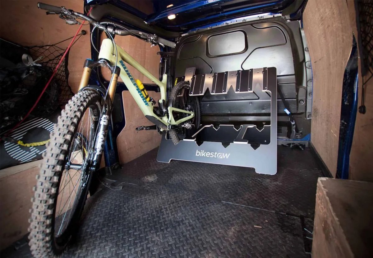 A professional tray-style bike rack mounted securely to the back of a camper van.