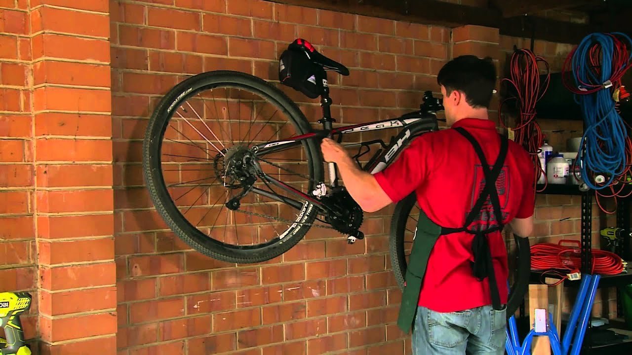 A modern bicycle mounted securely on a clean garage wall using a bike rack.