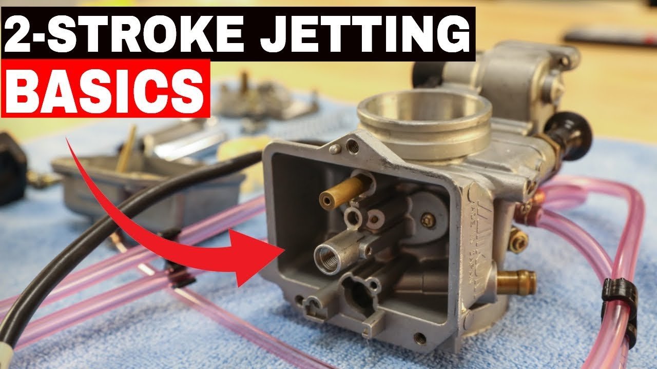 Disassembled parts of a two-stroke dirt bike carburetor laid out on a workshop bench.