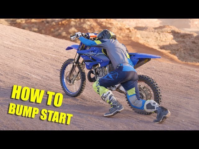 Jumper cables connected to a dirt bike battery to perform a jump start.