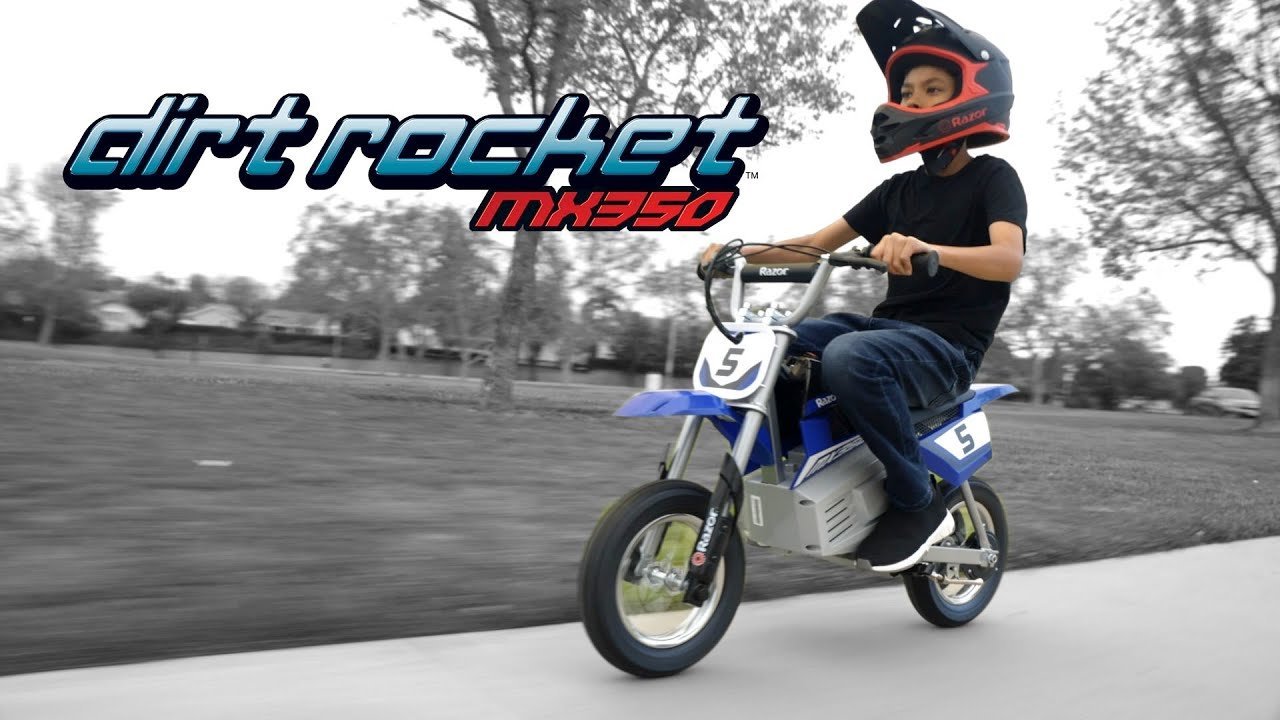 A person carefully disconnects the charging cable from an electric dirt bike.