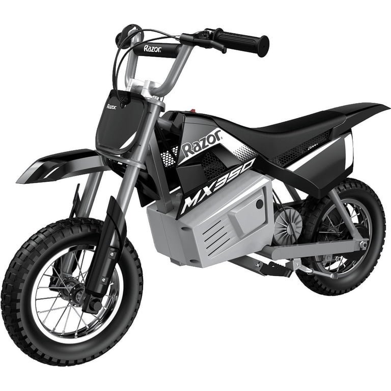 A rider stands beside their electric dirt bike in a sunny backyard.