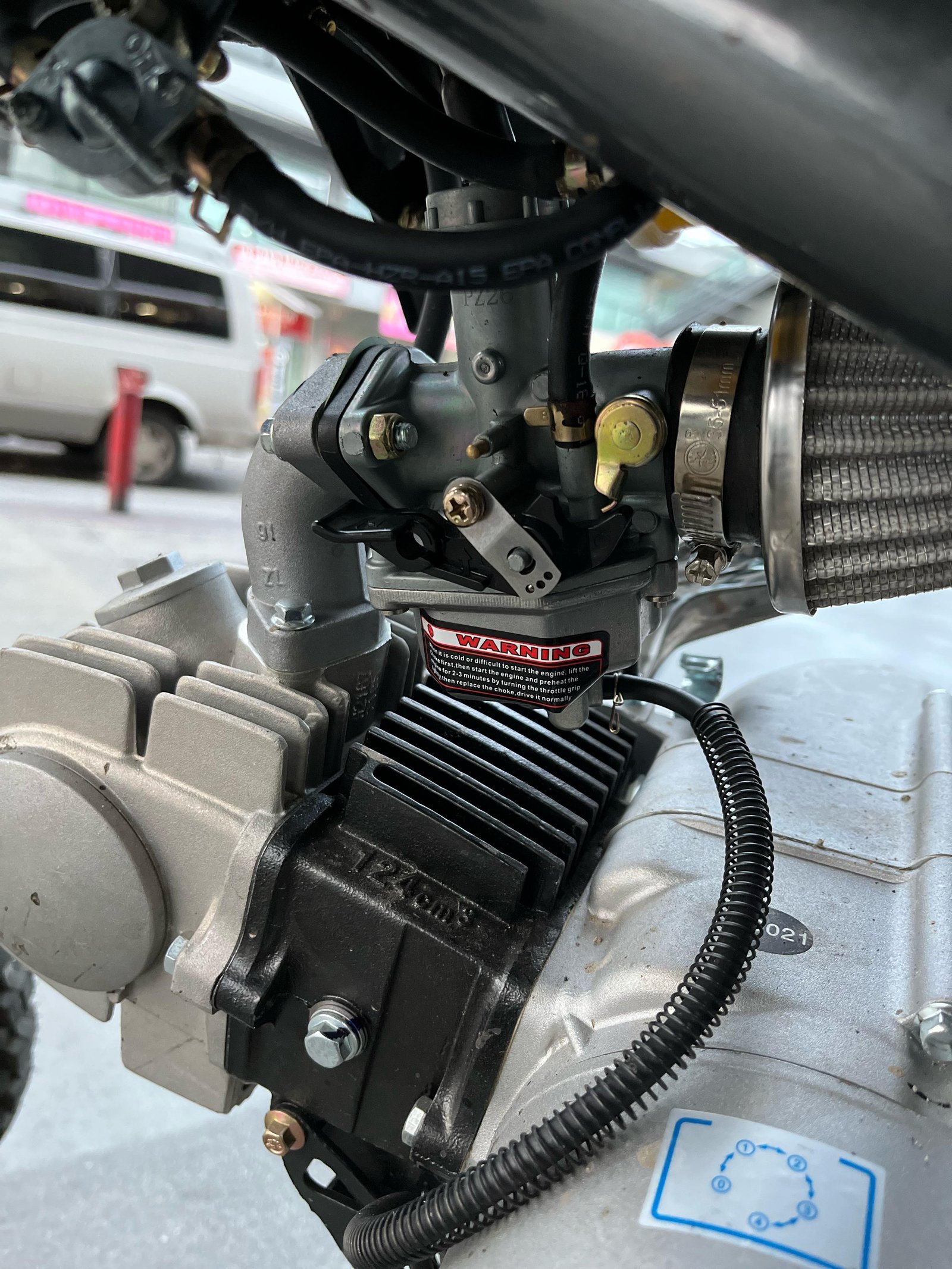 A gloved hand pulling the choke plunger on a dirt bike engine.