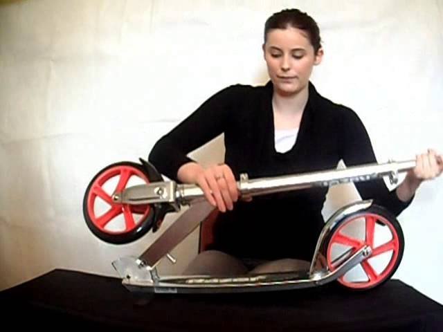 A person testing the stability of the scooter stem by applying pressure.